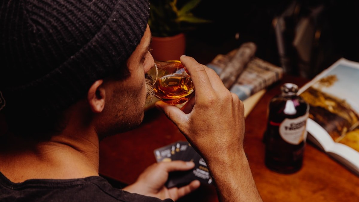 Man in black knit cap holding clear glass mug. — a Sleep Finally guide to The Honest Scale: Weighing Your Drink Against Your Night.