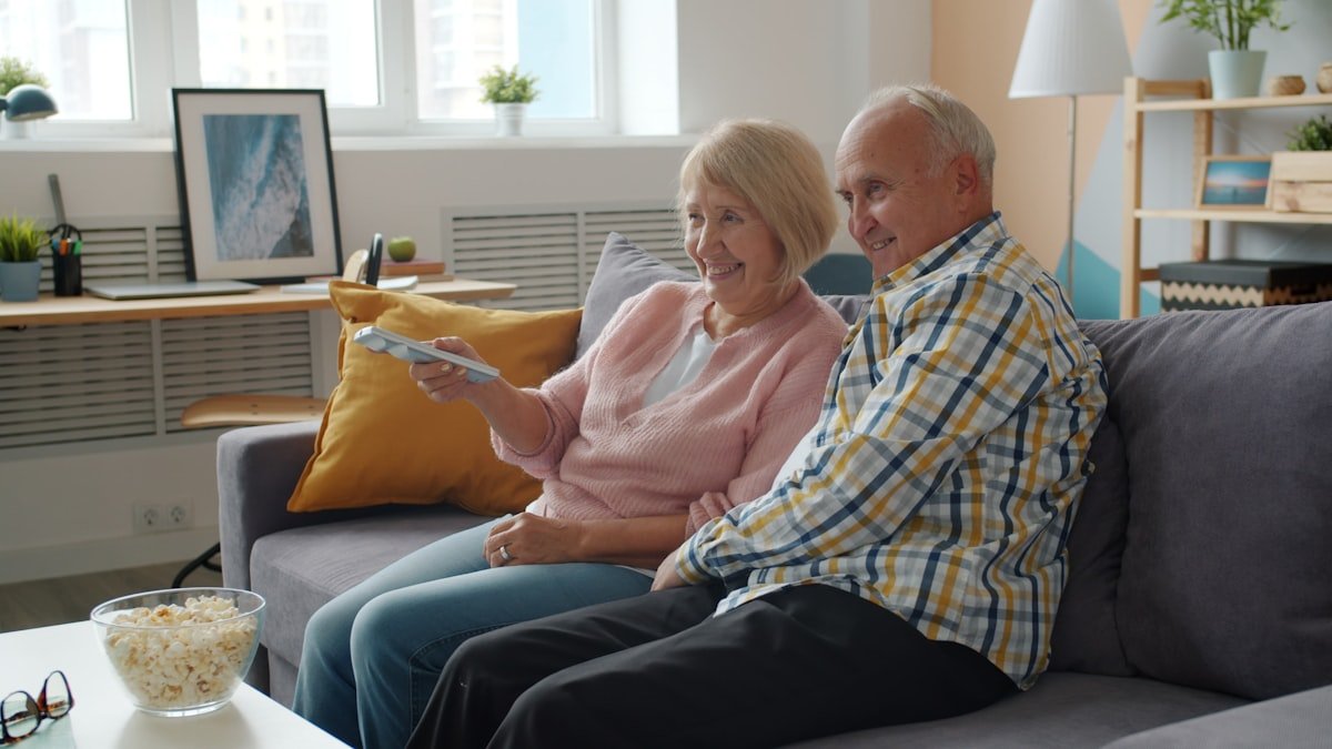 Elderly couple watching television on sofa with popcorn. — a Sleep Finally guide to The Show That Auto-Played: A Bedtime Story.
