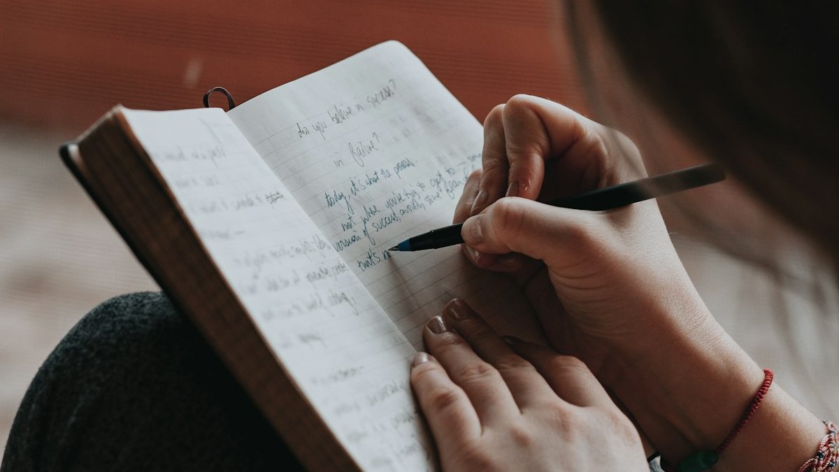 Woman writing in notebook with pen. — a Sleep Finally guide to The Worry Journal Method: Sleep Through the Night.