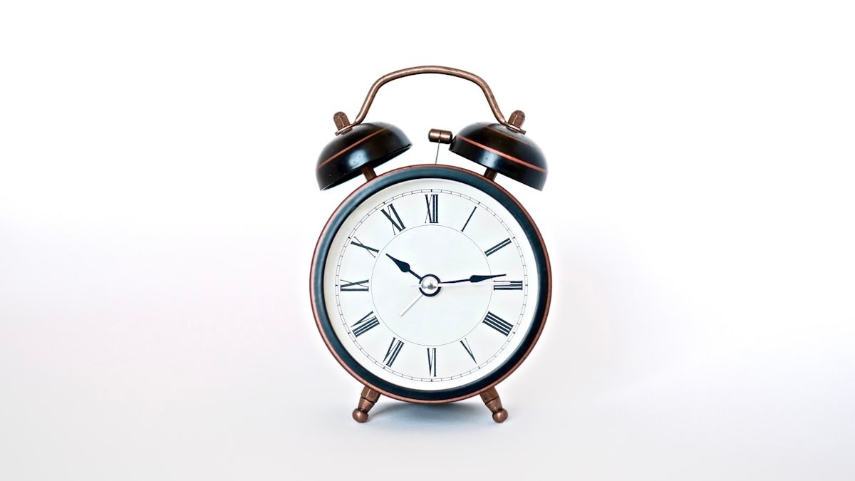 Round black and white analog alarm clock. — a Sleep Finally guide to Using an Alarm Clock Instead of Your Phone: First Week.