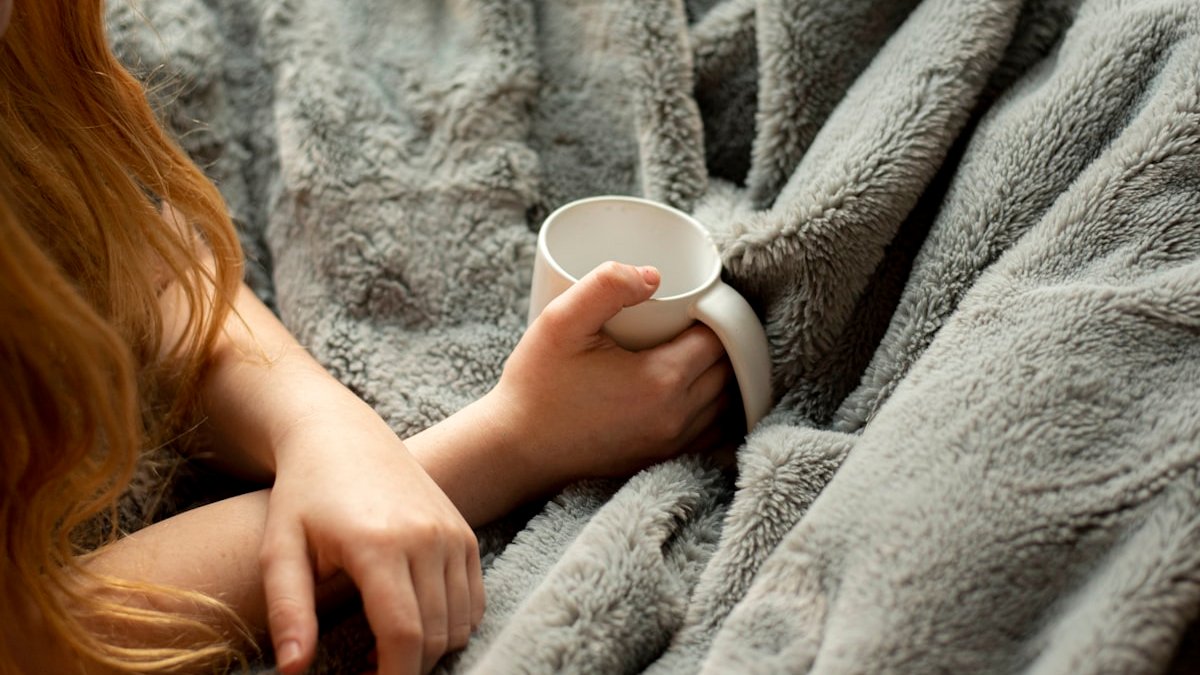 Woman holding white ceramic mug. — a Sleep Finally guide to Weighted Blankets for Stress: Do They Improve Sleep.