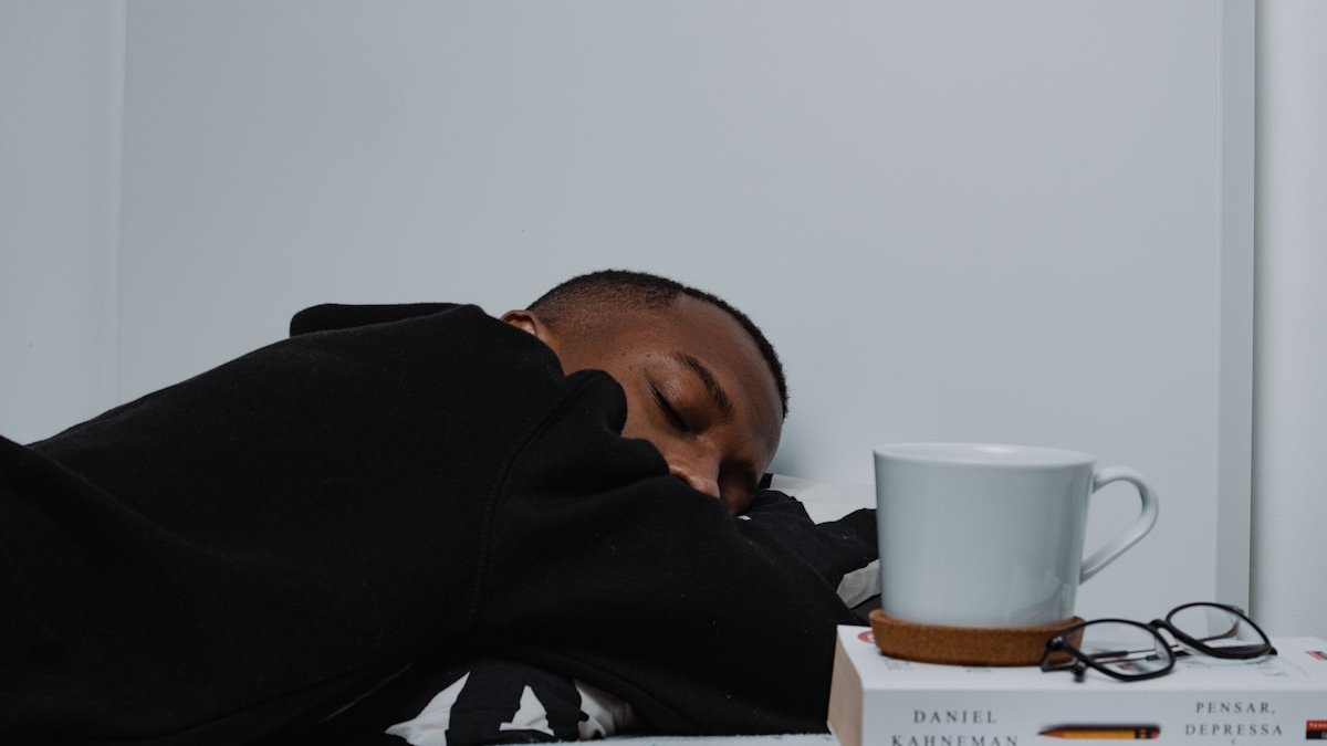 A man sleeping on a bed next to a stack of books. — a Sleep Finally guide to What Happens to Sleep After Two Weeks Without Alcohol.