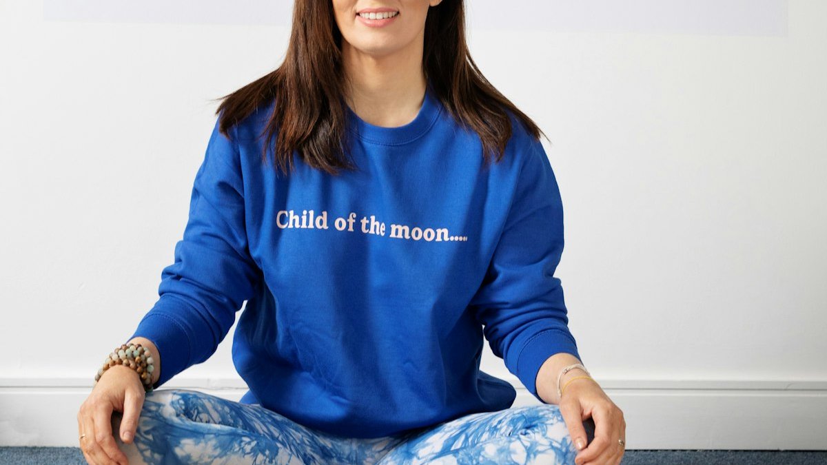 A woman in a blue shirt is sitting in a yoga pose. — a Sleep Finally guide to What Is CBT-I? The Insomnia Fix You've Never Heard Of.