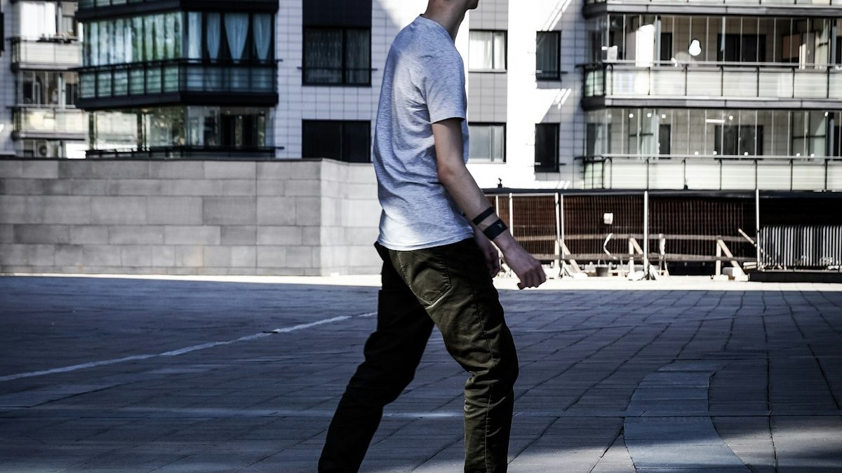 Man walking on gray brick pavement near white building. — a Sleep Finally guide to What the Lunchtime Walk Fixed: A Desk Worker Story.