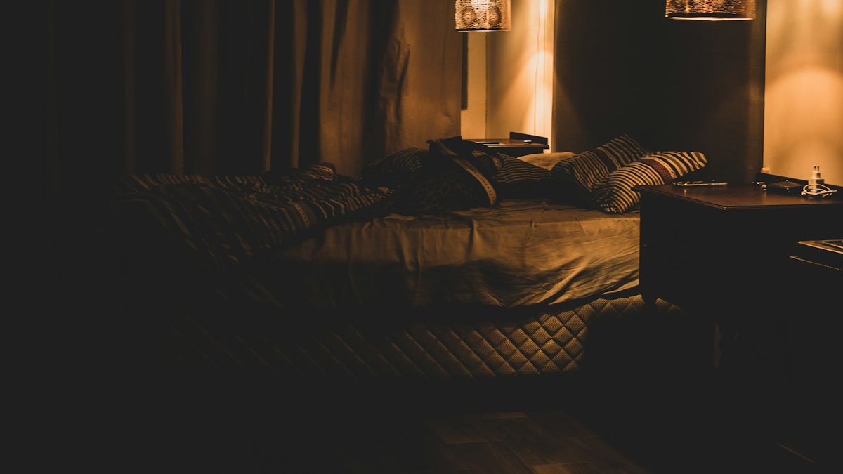 A dimly lit room with a bed and two lamps. — a Sleep Finally guide to When Night Wakings Become Chronic Insomnia.