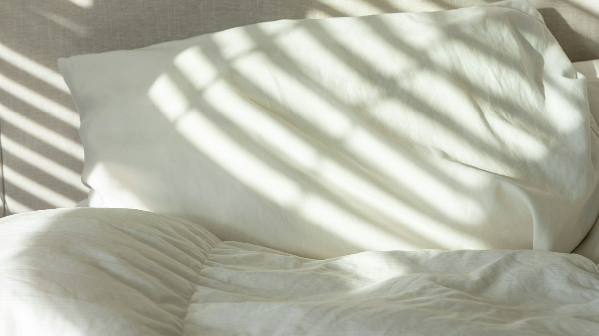 A bed with white sheets and white pillows. — a Sleep Finally guide to Which Bedding Is Best for Night Sweats.