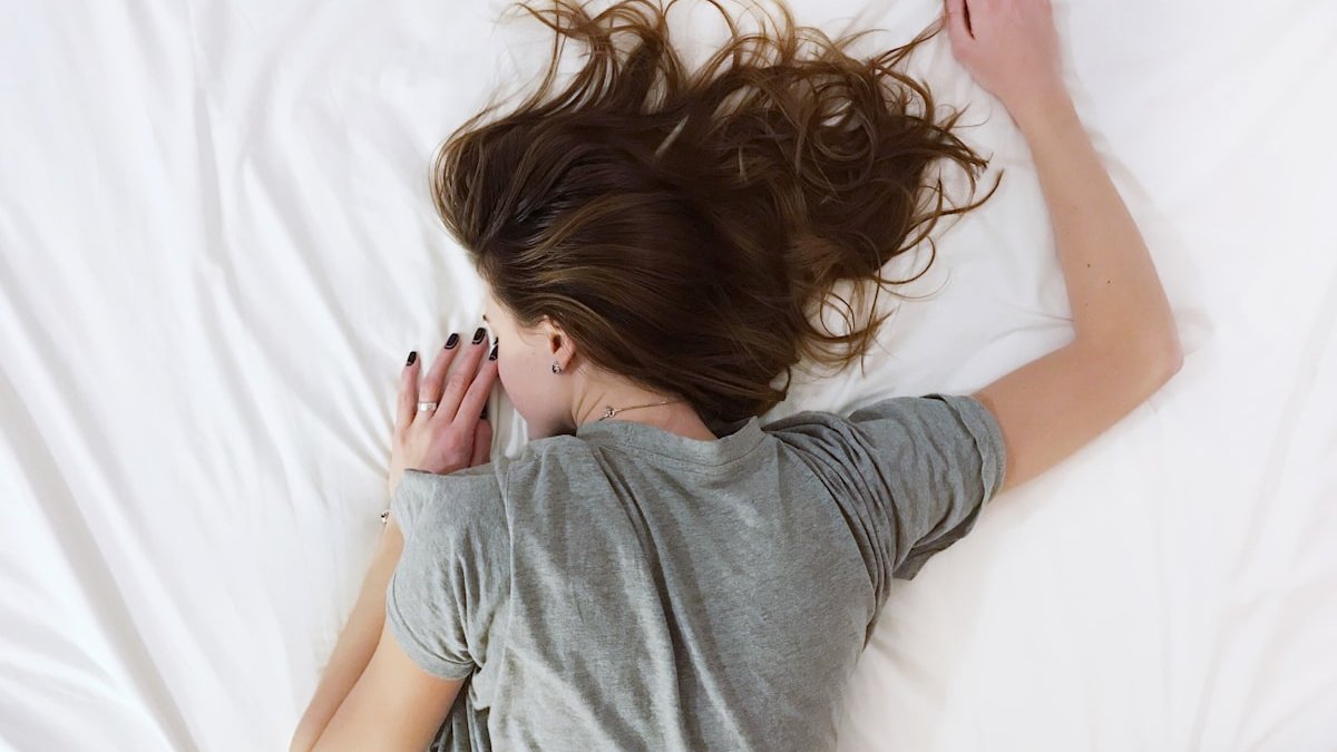 Woman laying on bed. — a Sleep Finally guide to Why Acid Reflux Wakes You Up at Night.