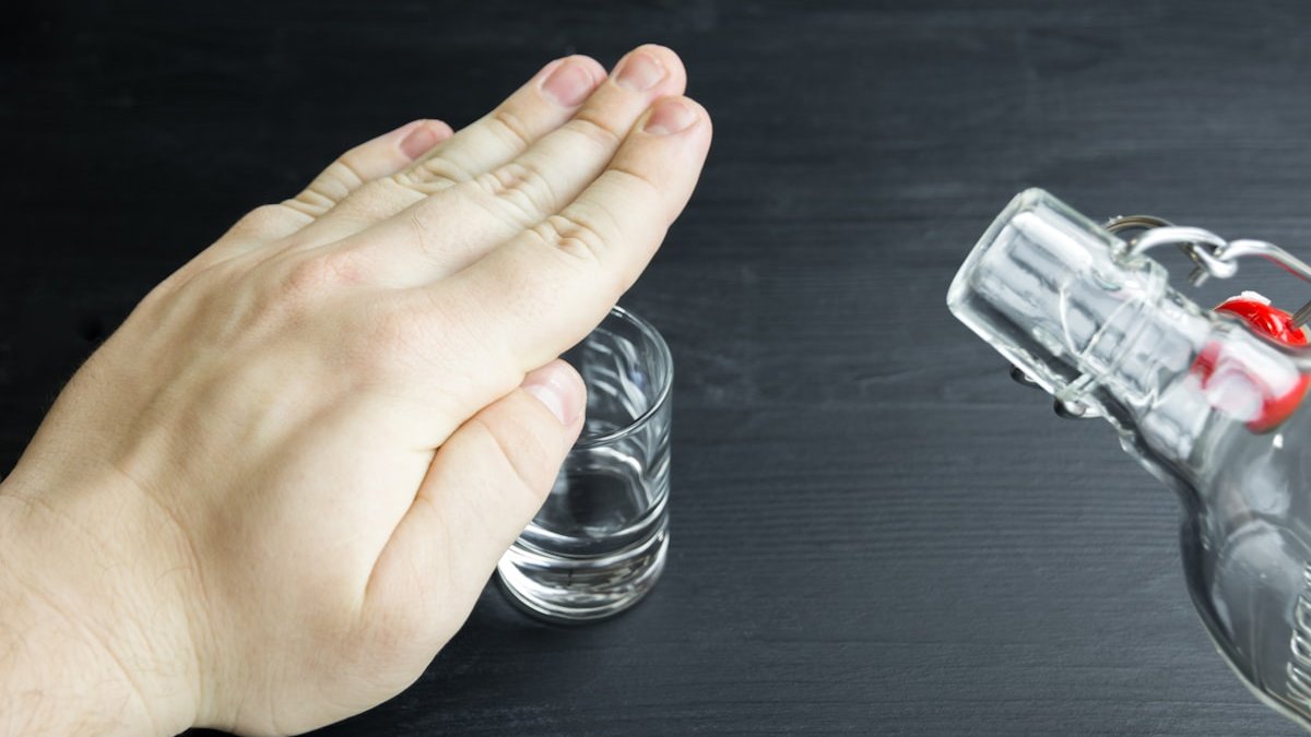 A hand reaching for a glass of water. — a Sleep Finally guide to Why Alcohol Puts You to Sleep Then Wakes You Up.