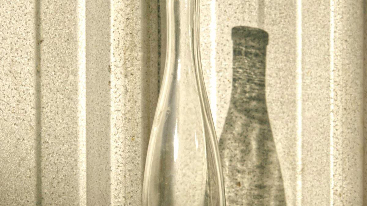Grayscale photo of glass bottle. — a Sleep Finally guide to Why Binge Nights Cost Three Nights of Sleep.