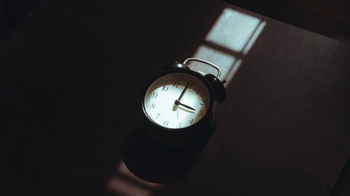 Alarm clock casting a shadow on a dark surface — a Sleep, Finally guide to Why Do I Wake Up at 3am Every Night?