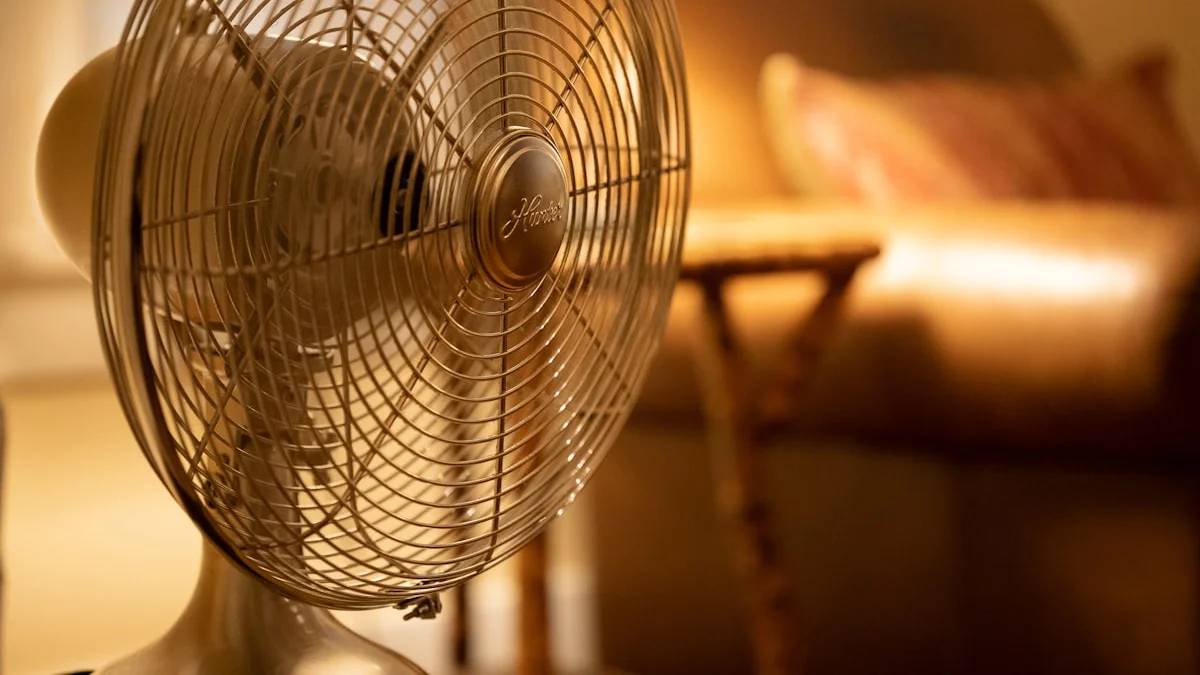 A metal desk fan with a wire cage in a warm sunlit room — a Sleep, Finally guide to Fan Noise and Sleep: Why Fans Help Some and Bother Others