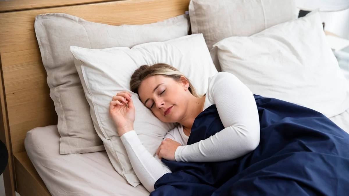 a woman sleeping on a bed with a blue blanket — a Sleep, Finally guide to Why Menopause Raises Your Sleep Apnea Risk