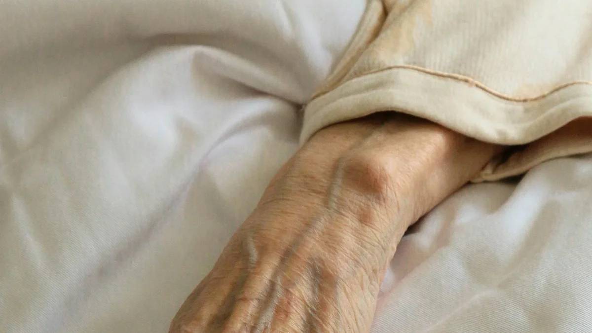 persons left hand on white textile — a Sleep, Finally guide to Why Night Wakings Increase With Age (And What Helps)